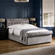 Gray upholstered bed in a bedroom with dark walls and a window.