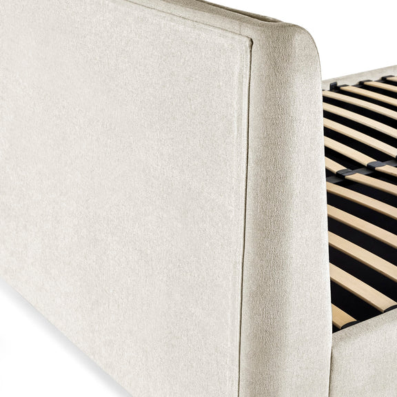Close-up of a beige upholstered headboard with wooden slats on a white background