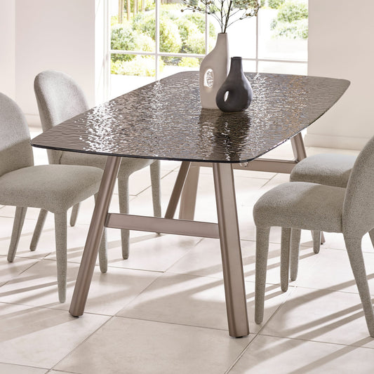 Dining table with textured glass top and metal legs in a bright room.