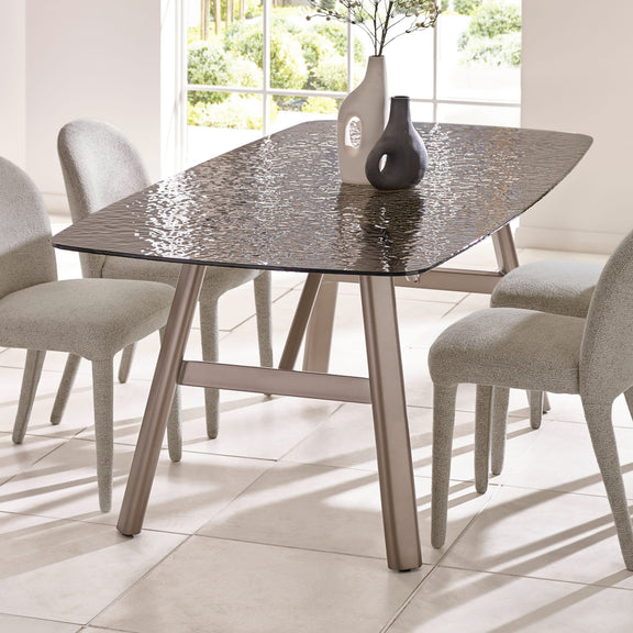 Dining table with textured glass top and metal legs in a bright room.