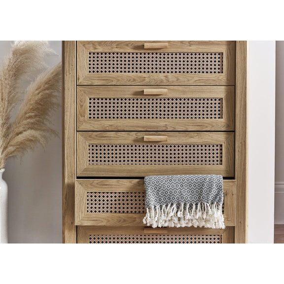 Wooden cabinet with woven design and a towel draped over it, with pampas grass on the side.