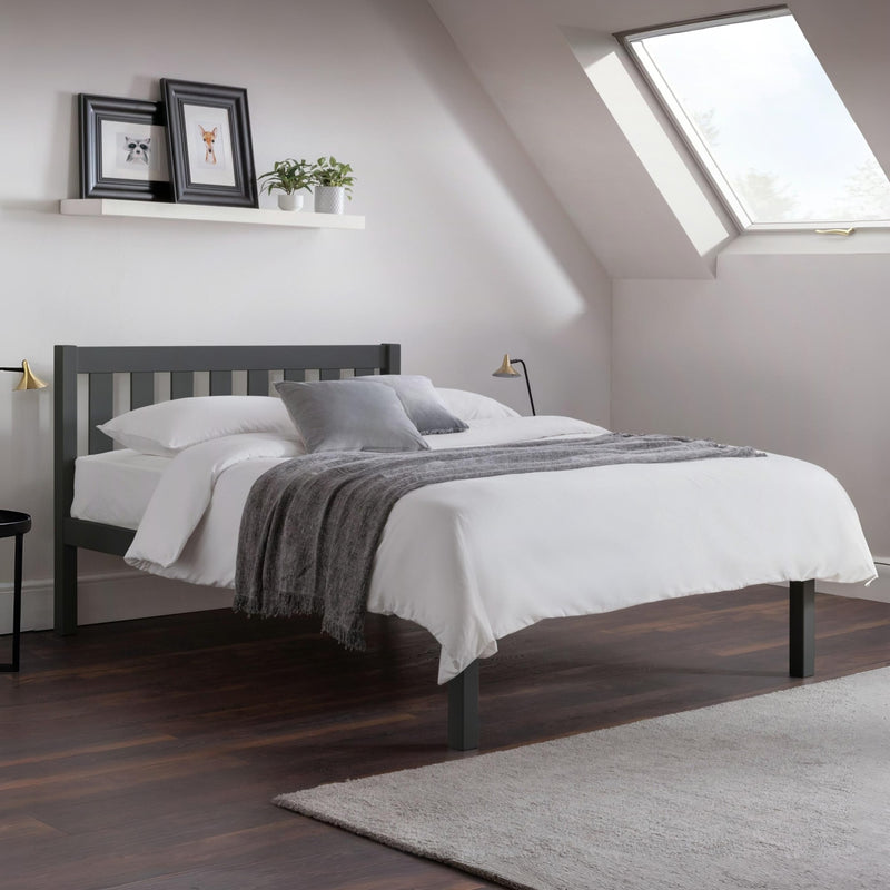 Bedroom with a bed featuring white bedding and gray blankets, under a skylight.