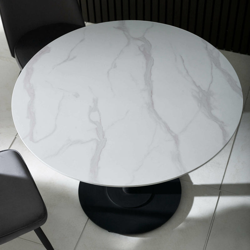 Round marble table with a black base on a tiled floor