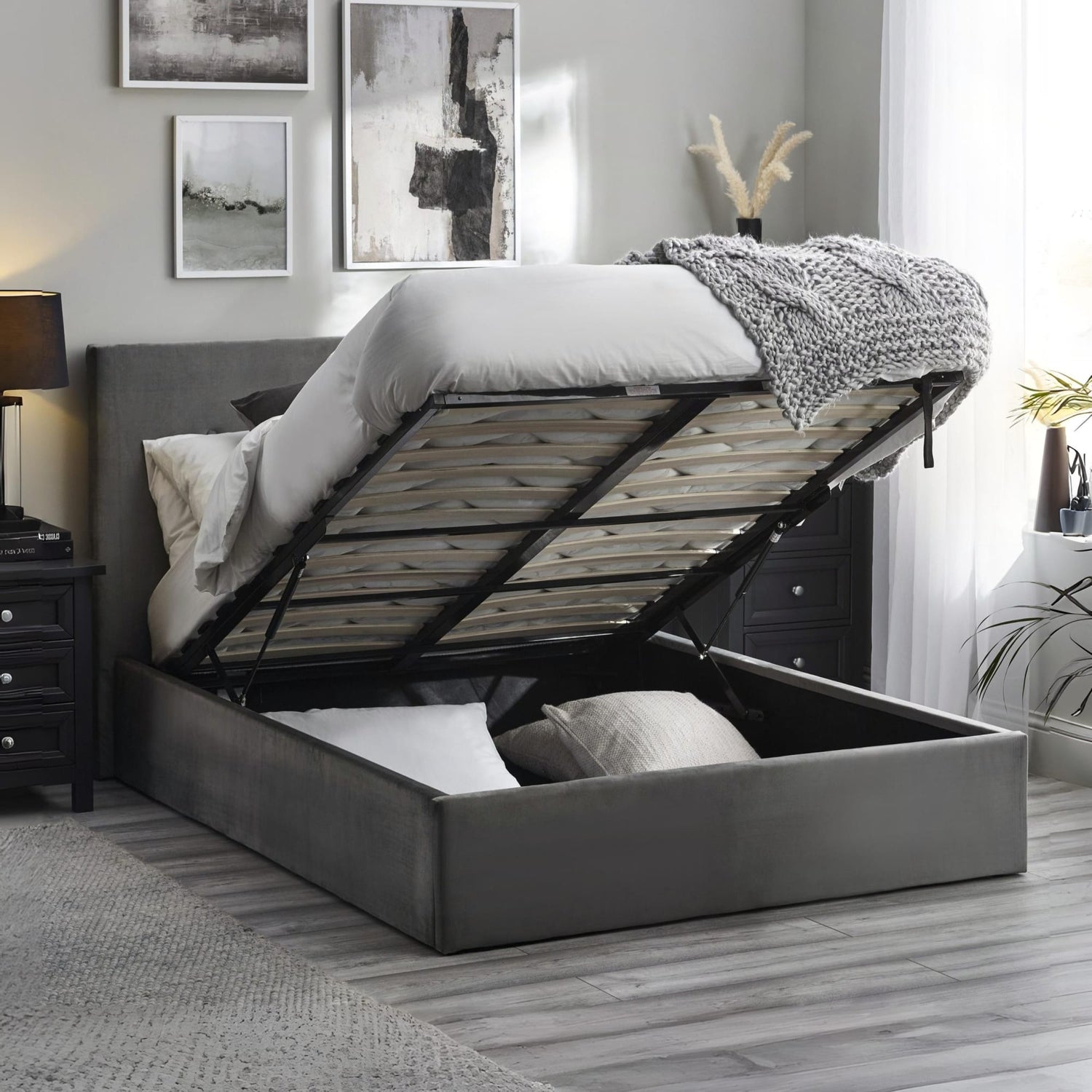 Gray upholstered bed with storage drawers in a bedroom setting.