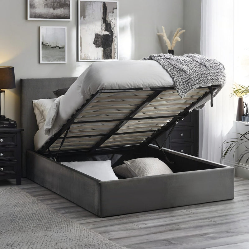Gray upholstered bed with storage drawers in a bedroom setting.