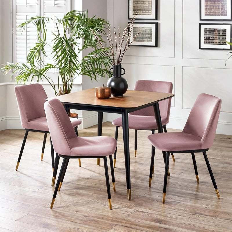 Dining room with a round wooden table and four pink chairs on a wooden floor.