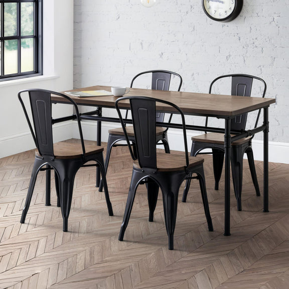 Dining set with wooden table and black metal chairs in a room with white brick walls and a clock.