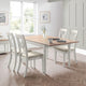 Dining room with a wooden table and white chairs in a bright room.