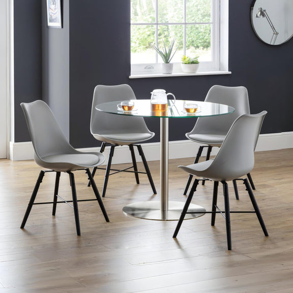 Dining room with a round glass table and four gray chairs on a wooden floor.
