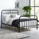 Black metal bed frame with white bedding in a room with a large window and plant.