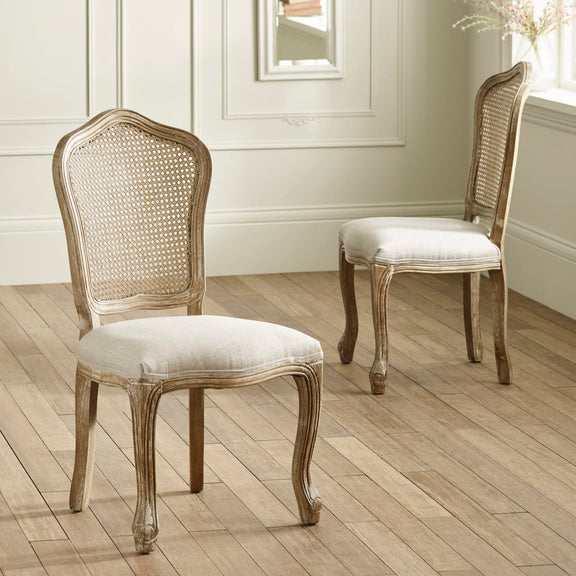 Two wooden chairs with wicker backrests and upholstered seats on a wooden floor.