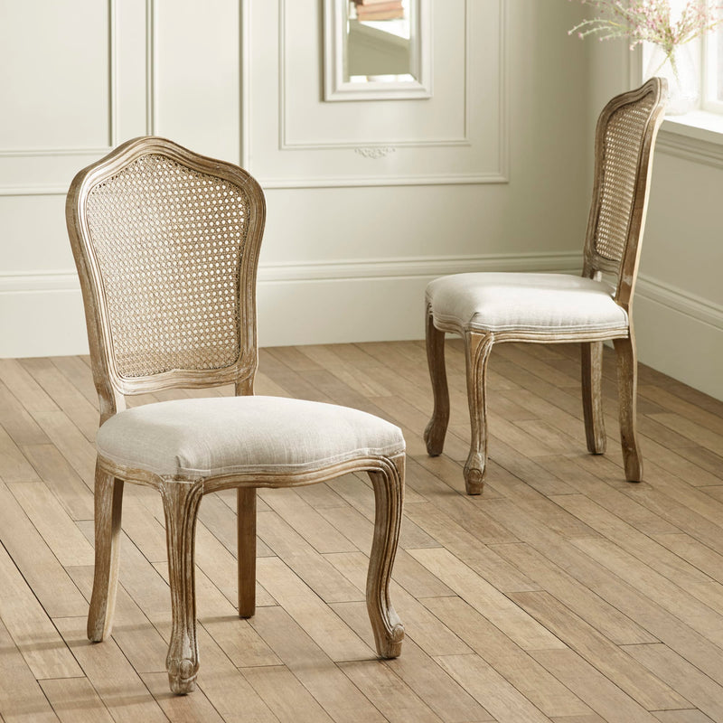 Two wooden chairs with wicker backrests and upholstered seats on a wooden floor.