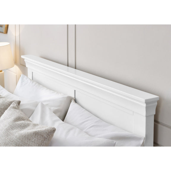 White wooden headboard with pillows on a bed in a bedroom setting