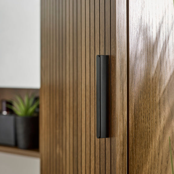 Close-up of a wooden cabinet with a black handle, blurred background