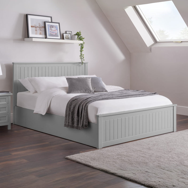Gray bed in a bedroom with a skylight and wooden flooring.
