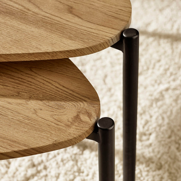 Close-up of a wooden side table with black metal legs on a textured white background