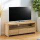 Wooden TV stand with a television on top in a room with plants and decor.