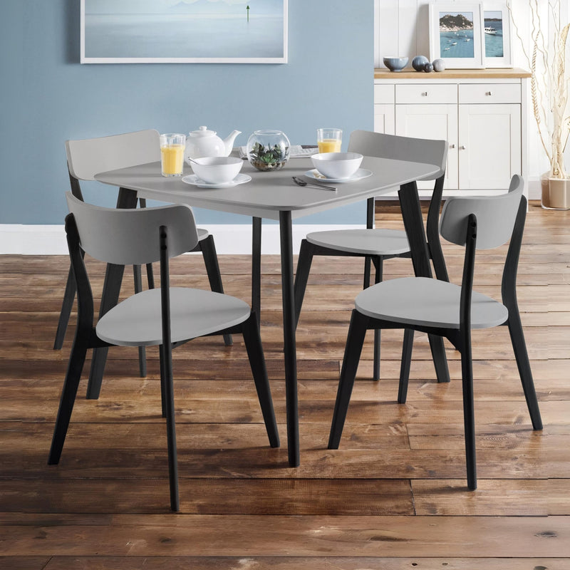 Dining table set with chairs in a room with wooden flooring and light blue walls.