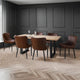 Dining room with wooden table and brown chairs against a dark paneled wall.