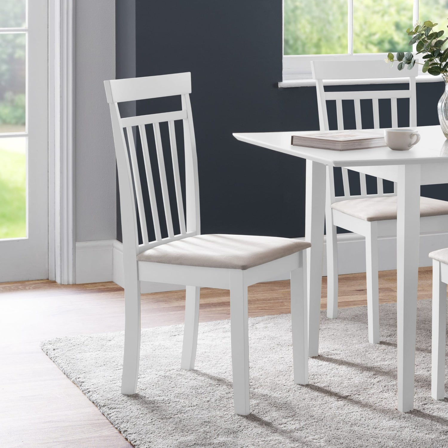 White dining chair with a cushioned seat in a room with a table and chairs.