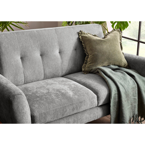 Gray sofa with a green pillow and blanket in a room with plants.