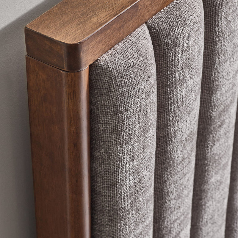 Close-up of a wooden headboard with textured fabric surface.