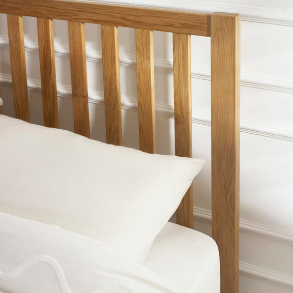 Wooden headboard with white bedding against a white wall