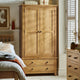 Wooden wardrobe with two doors and two drawers in a bedroom setting.