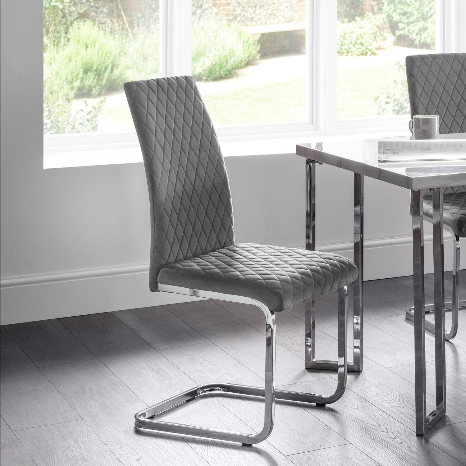 Gray quilted chair with chrome legs in a modern dining room setting