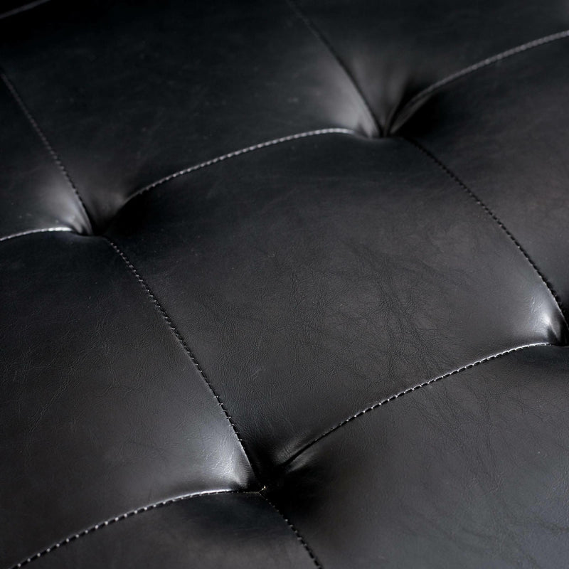 Close-up of a black leather sofa with tufted design