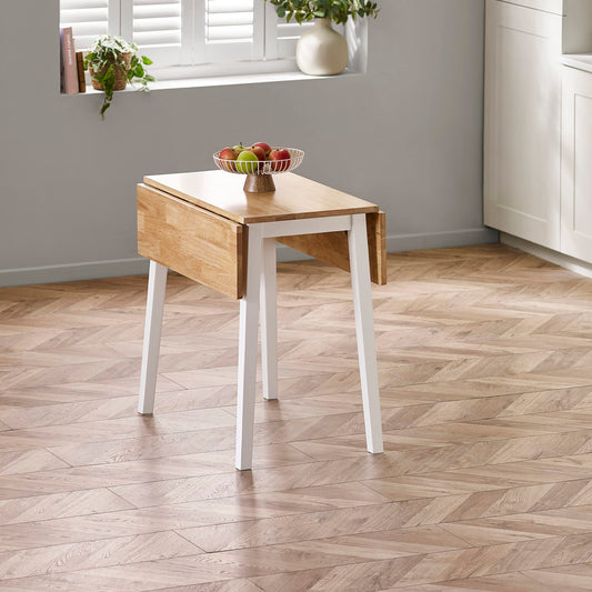 Wooden side table with a white base on a herringbone wood floor.