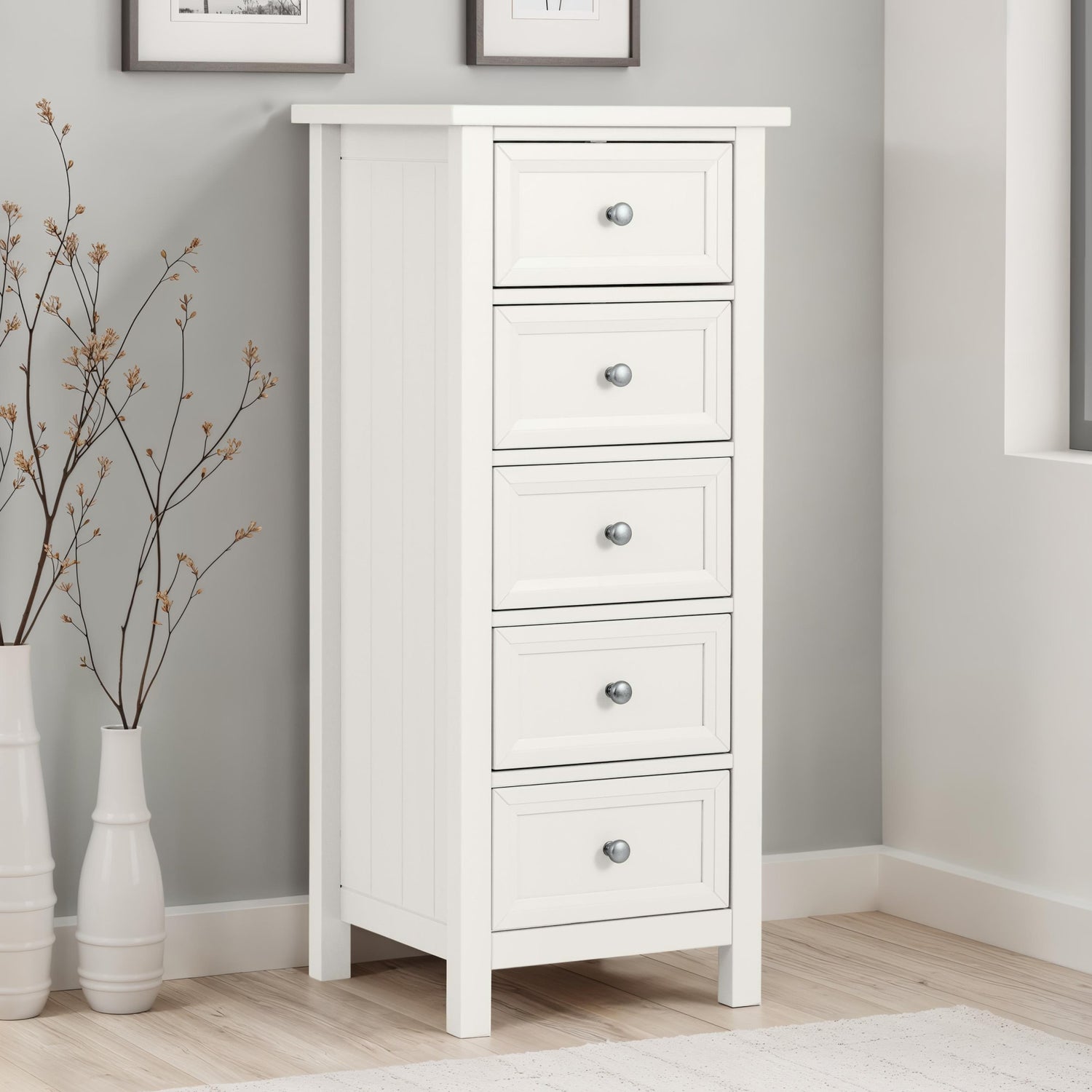 White dresser with four drawers in a room with gray walls and wooden flooring.