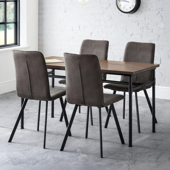 Dining table with four brown chairs in a room with white brick walls and a window.