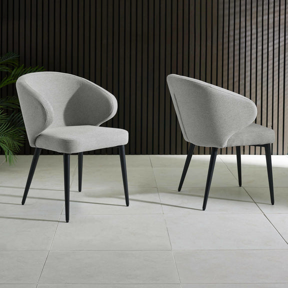 Two gray chairs with black legs on a light gray floor against a dark wooden paneled wall.