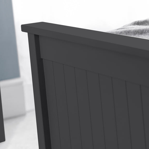 Close-up of a dark gray wooden bed frame against a light background