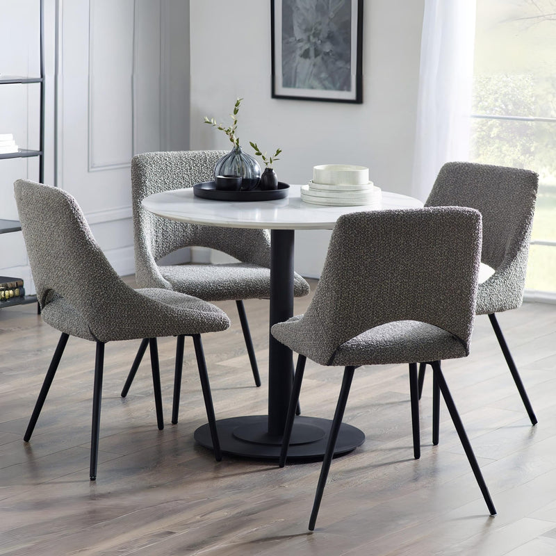 Round dining table with four gray chairs in a modern room.
