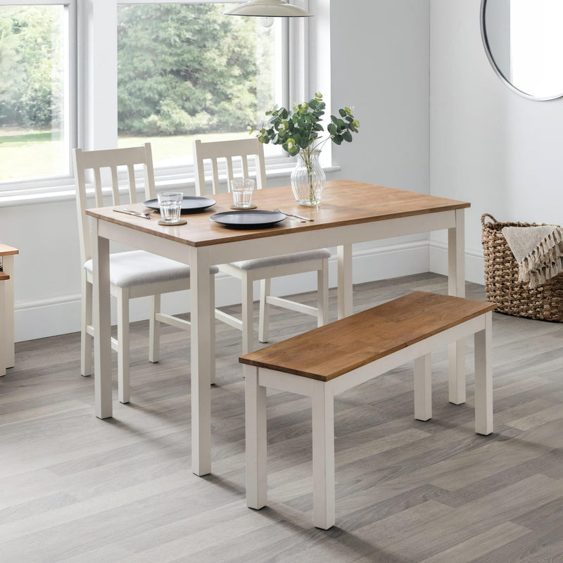 Dining set with table, chairs, and bench in a room with large windows.