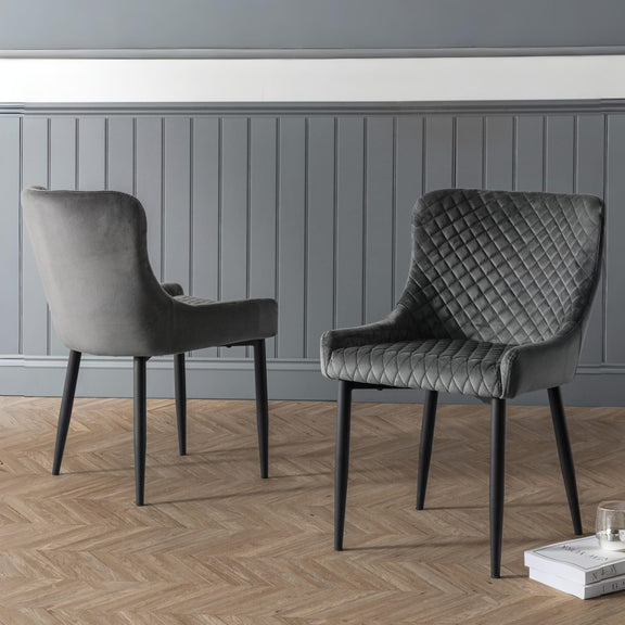 Two gray chairs in a room with a gray paneled wall and wooden floor.
