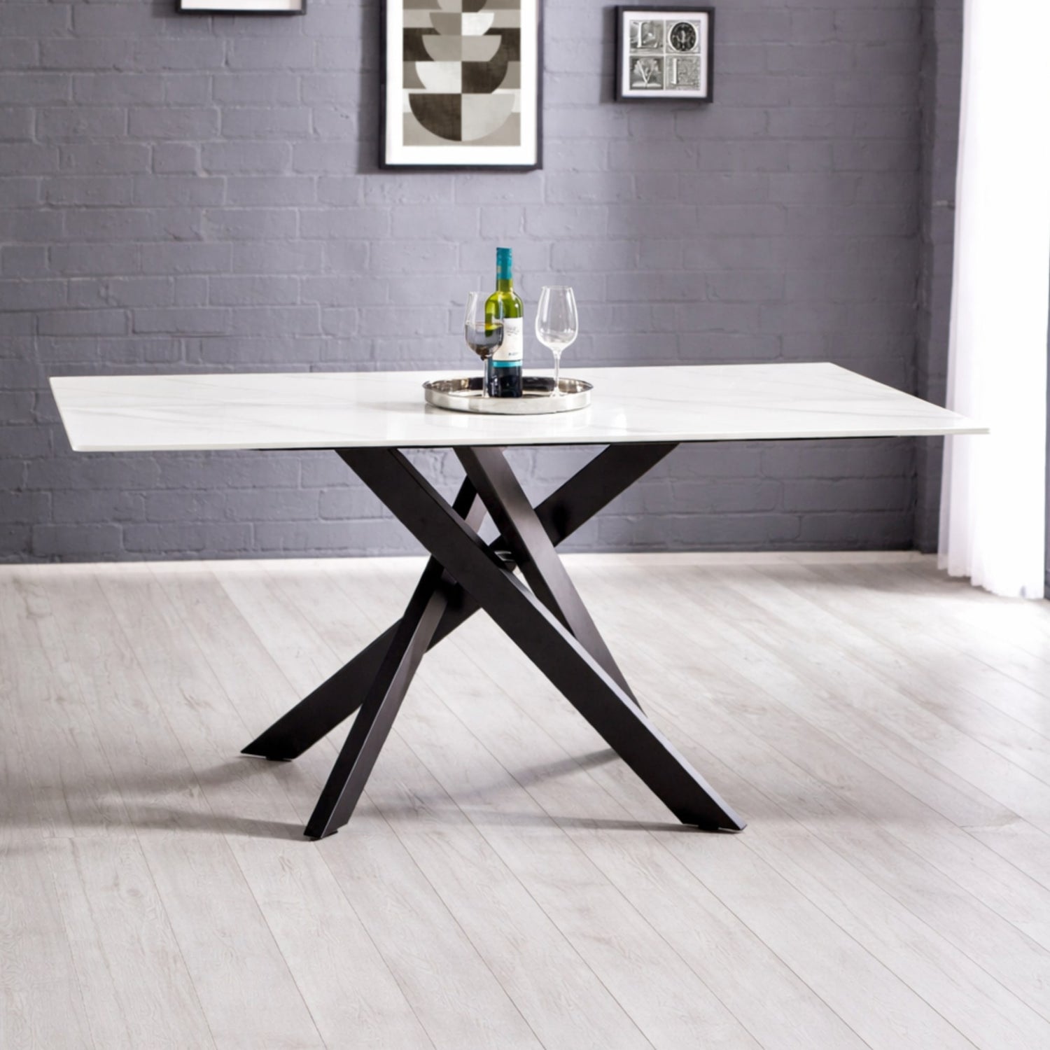 Modern dining table with black legs and white top in a room with gray walls and white floor.