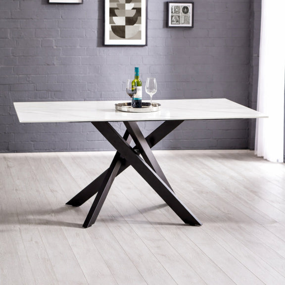 Modern dining table with black legs and white top in a room with gray walls and white floor.