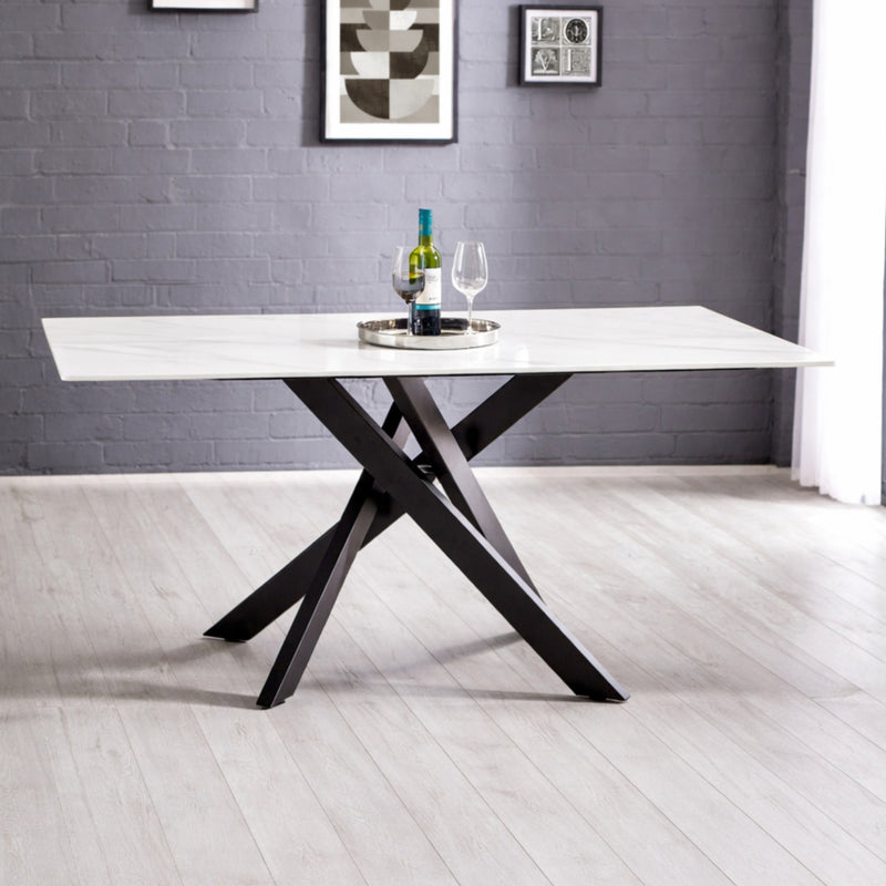 Modern dining table with black legs and white top in a room with gray walls and white floor.