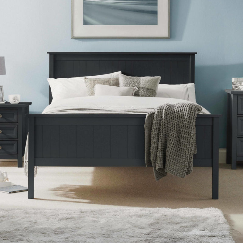 Black bed frame with white bedding and gray throw blanket in a bedroom setting.