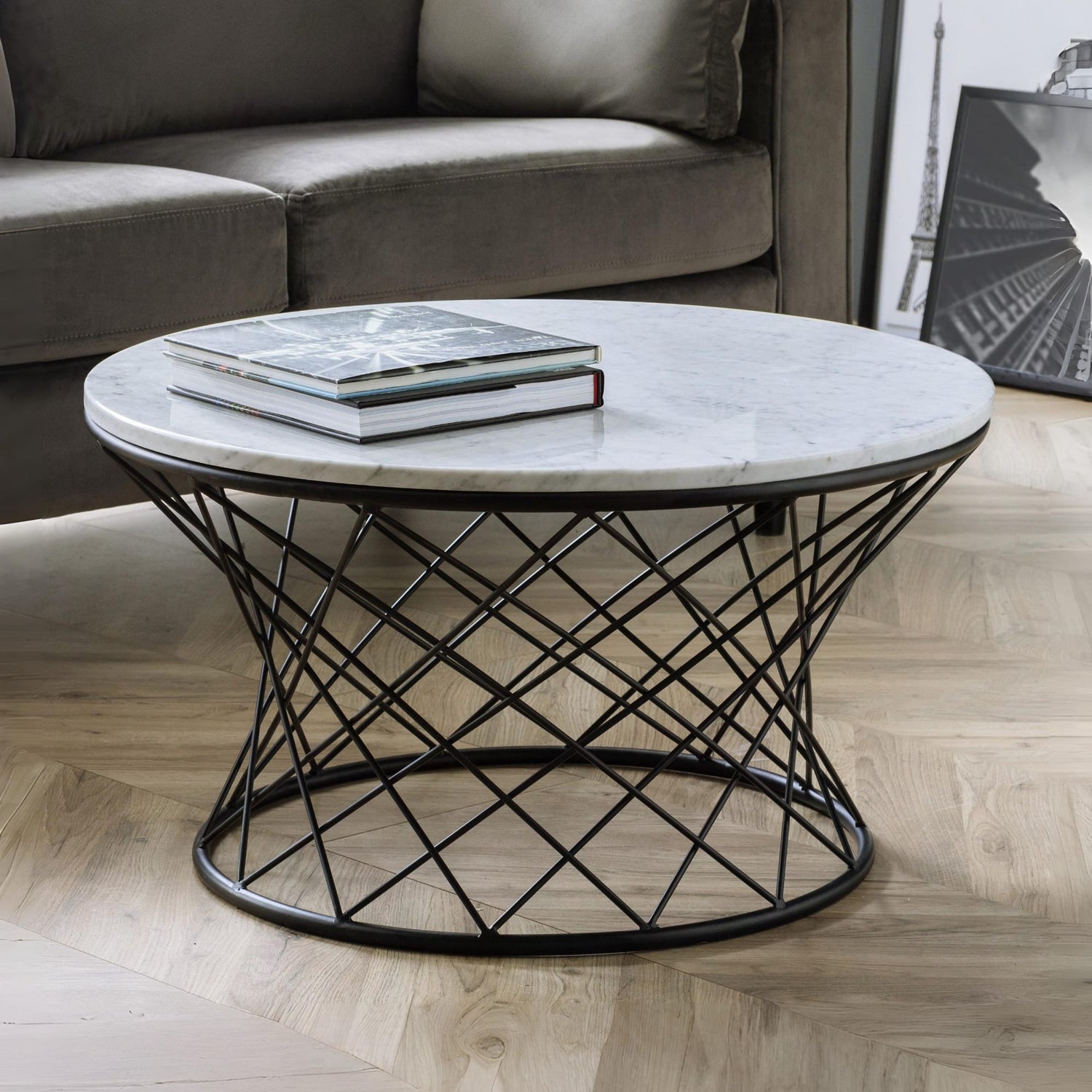 Round marble coffee table with black metal base in a living room setting