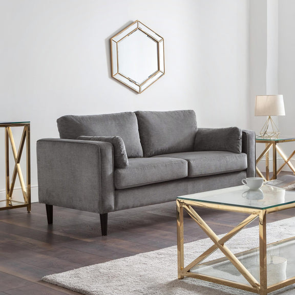 Gray sofa in a modern living room with gold accents and a hexagonal mirror.