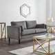 Gray sofa in a modern living room with gold accents and a hexagonal mirror.