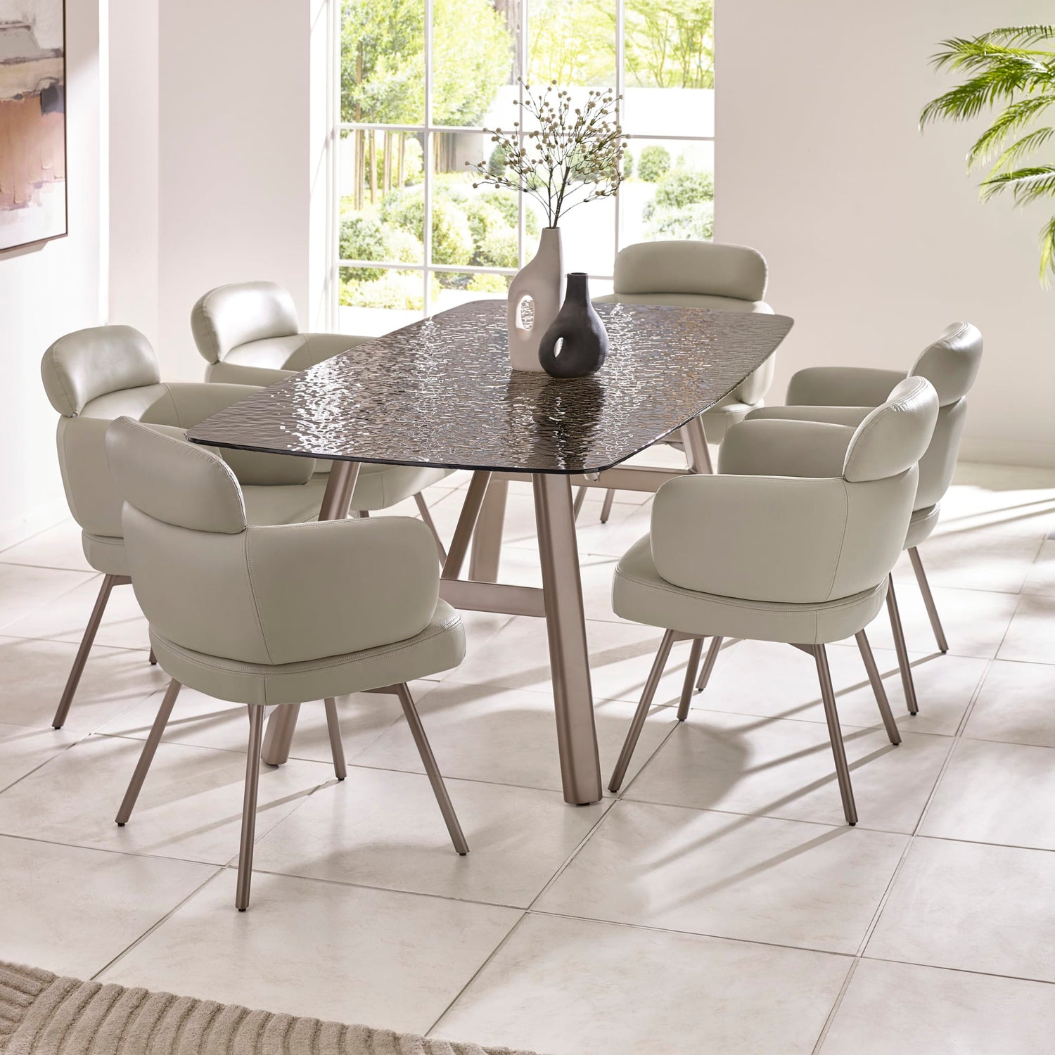 Dining room with a round glass table and eight chairs in a bright room.