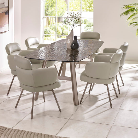 Dining room with a round glass table and eight chairs in a bright room.