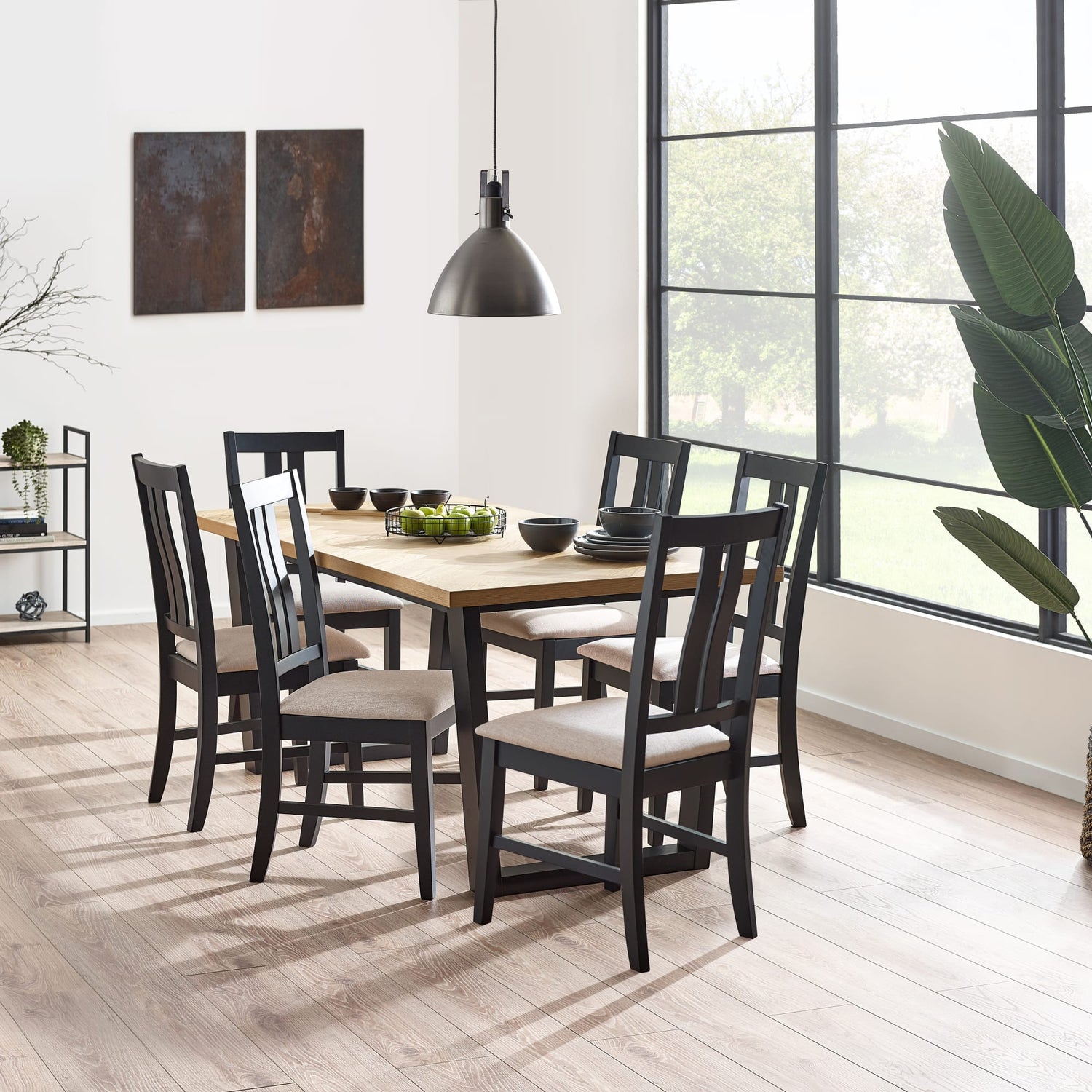 Dining room with wooden table and chairs near a large window.