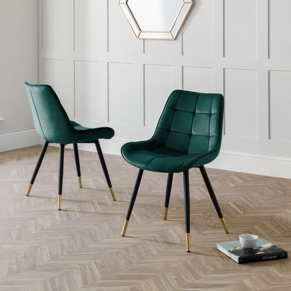 Two green chairs with black legs on a wooden floor.