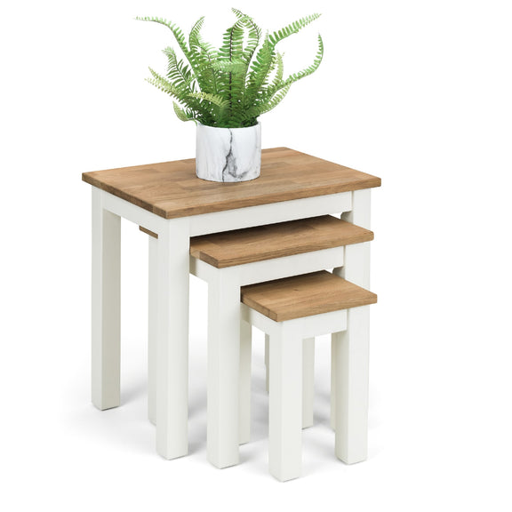Set of three nesting tables with wooden tops and white bases, one with a potted plant.